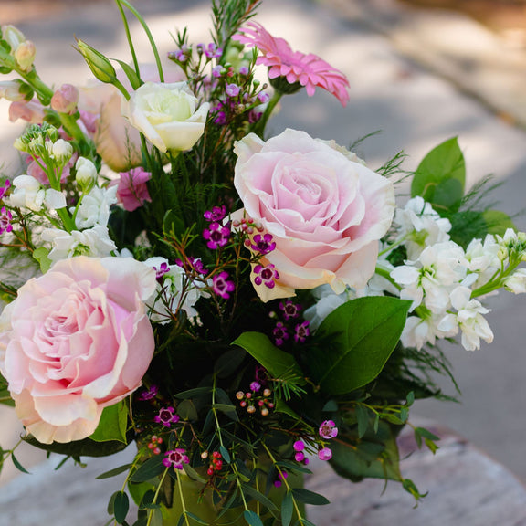 Bouquet of pink and white flowers with green leaves on a wooden surface