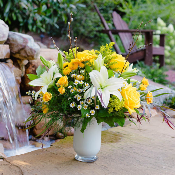 Floral arrangement in a vase on a stone surface with a garden background