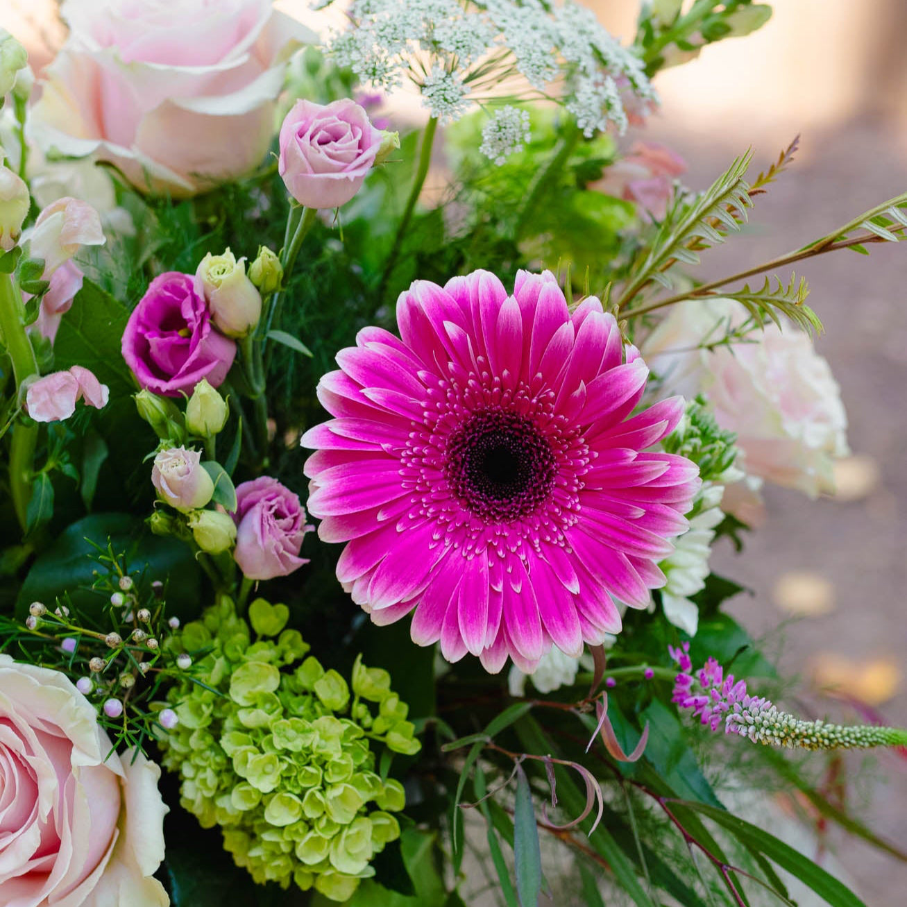 Bouquet of flowers with a prominent pink Gerbera daisy, surrounded by other flowers and greenery.