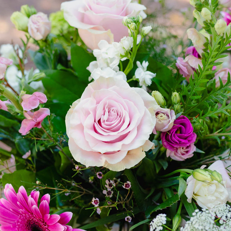 Bouquet of pink and white roses, greenery, and a pink gerbera daisy.