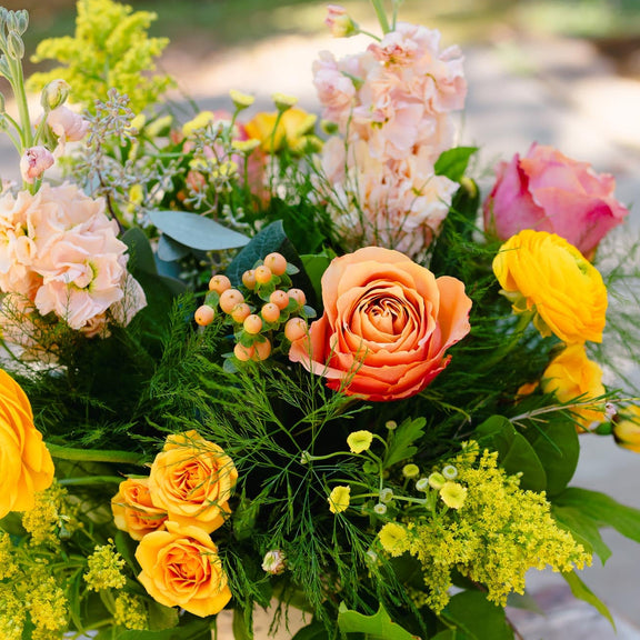 Bouquet of colorful flowers including roses and hydrangeas on a wooden surface.
