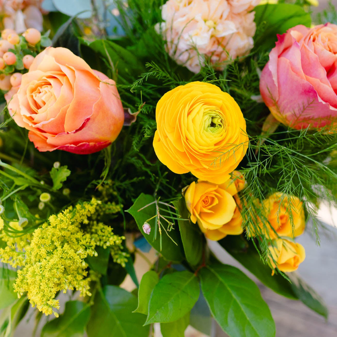 Bouquet of colorful flowers including yellow, pink, and green in a natural setting.