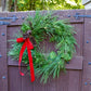 Green wreath with red ribbon on a wooden gate