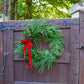 Green wreath with a red bow on a wooden gate outdoors