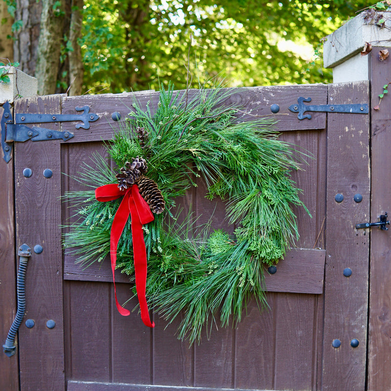 Green wreath with a red bow on a wooden gate outdoors