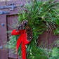 Green wreath with pine cones and a red ribbon on a wooden door