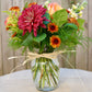 Bouquet of flowers in a clear vase with a decorative bow on a neutral background