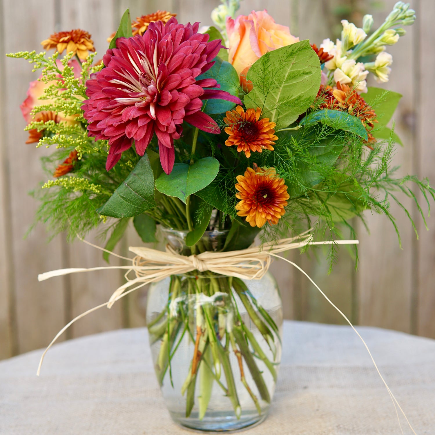 Bouquet of flowers in a clear vase with a decorative bow on a neutral background
