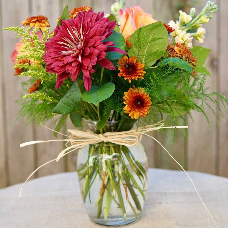 Bouquet of flowers in a clear vase with a decorative bow on a neutral background