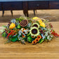 Autumnal flower arrangement with sunflowers, pumpkins, and berries on a wooden surface.