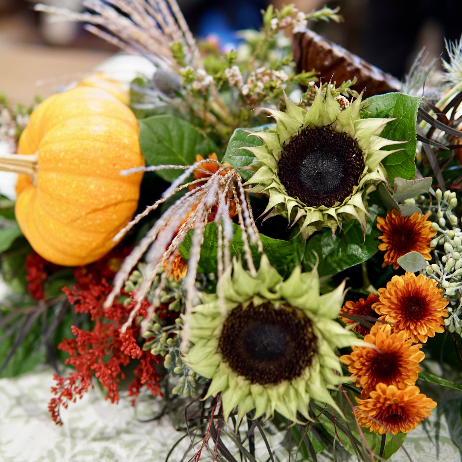 Autumn-themed floral arrangement with pumpkins and sunflowers.