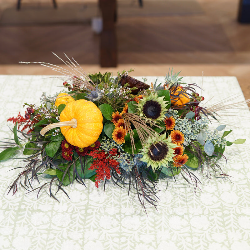 Decorative floral arrangement with pumpkins on a white tablecloth