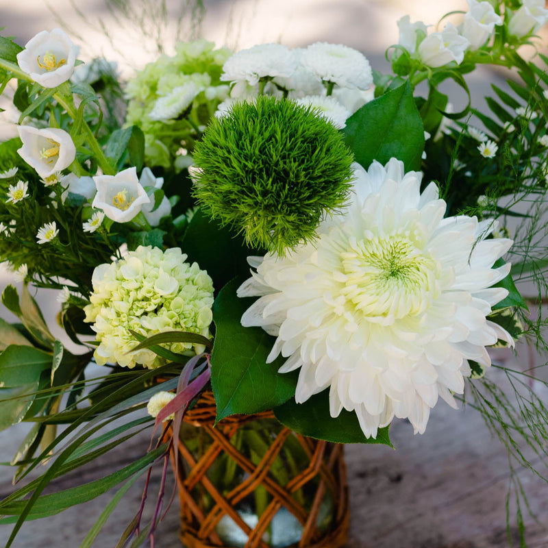 Bouquet of flowers in a woven basket on a wooden surface