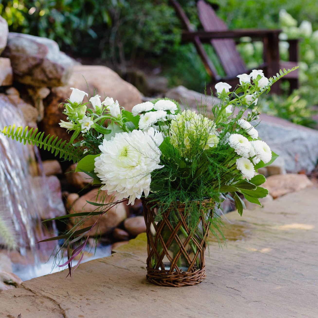 Bouquet of white flowers in a woven basket on a stone surface with a natural background