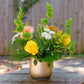 Floral arrangement in a vase on a wooden table with a blurred natural background