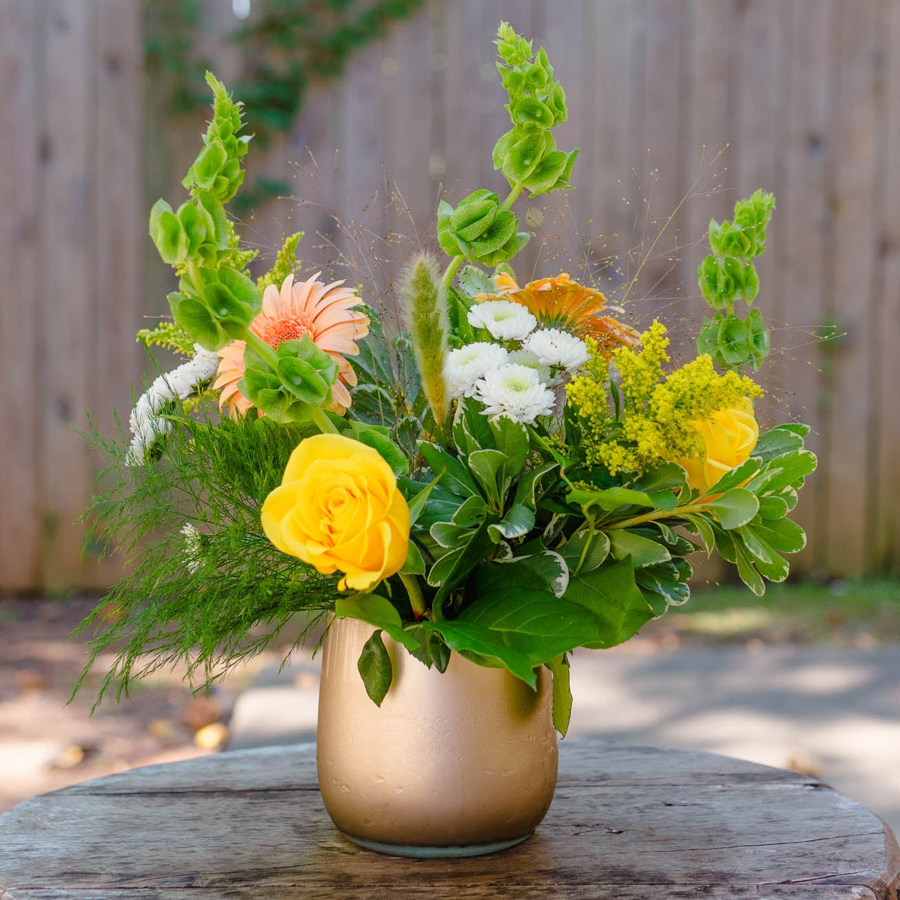Floral arrangement in a vase on a wooden table with a blurred natural background