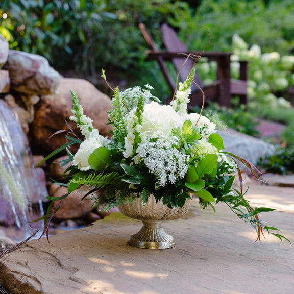 Floral arrangement in a decorative vase on a stone surface with a natural background