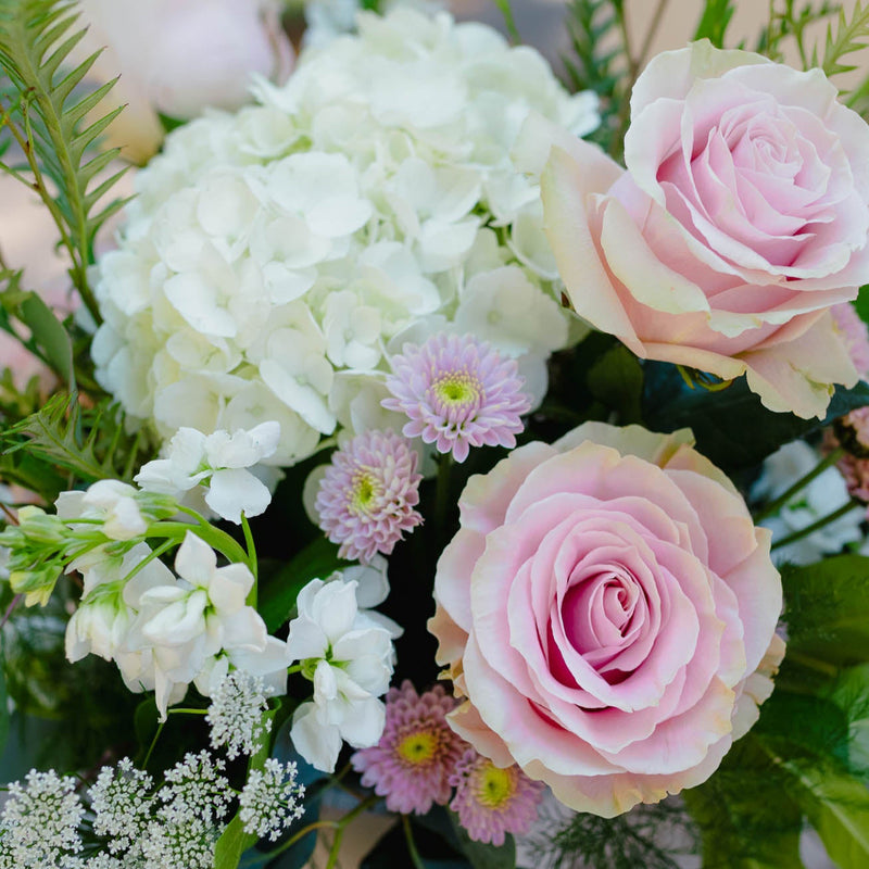 Bouquet of pink and white flowers with greenery on a wooden surface