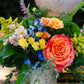 Colorful bouquet of flowers with a pink rose in a vase.