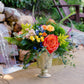 Colorful floral arrangement in a decorative vase by a water feature