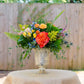 Colorful floral arrangement in a decorative vase on a table outdoors.
