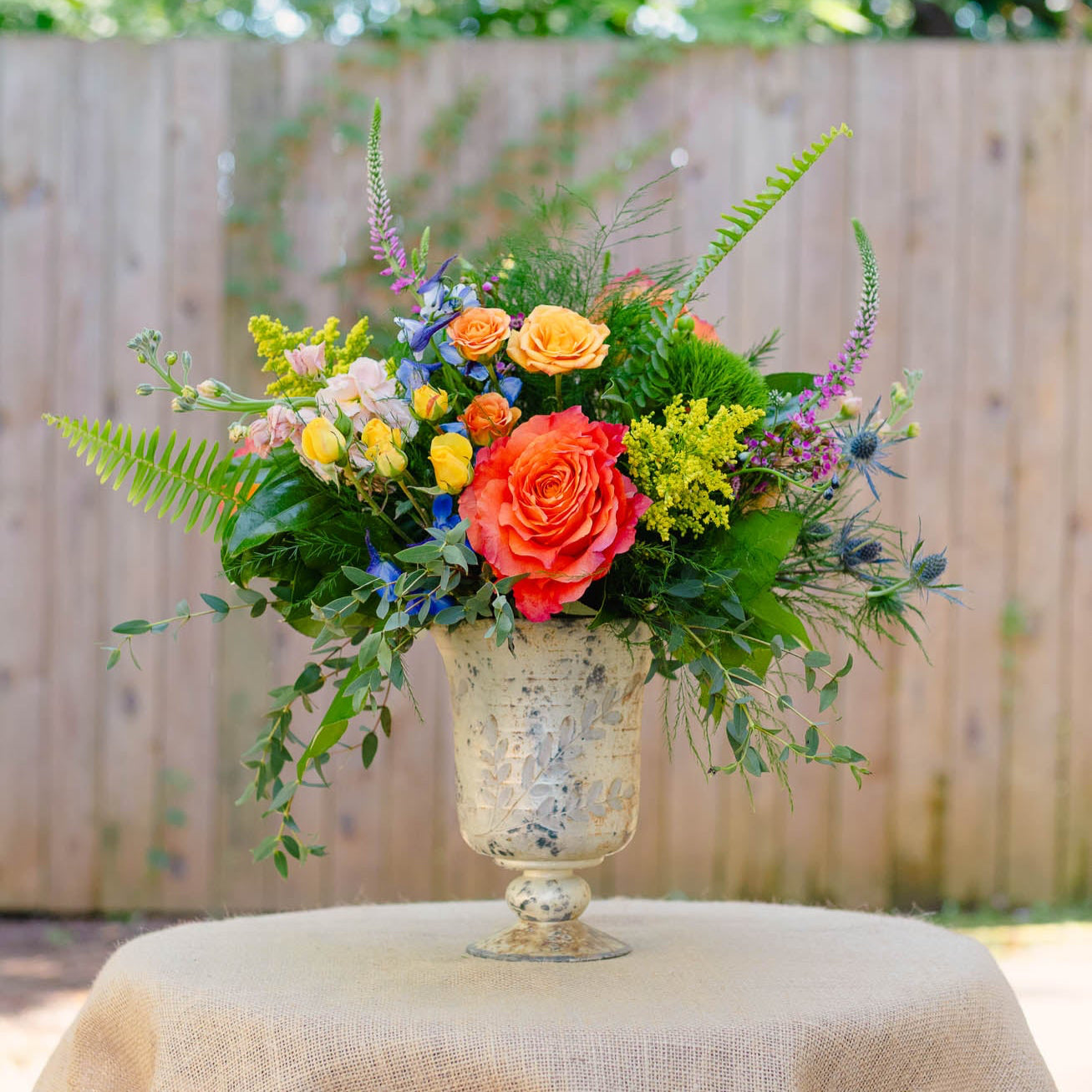 Colorful floral arrangement in a decorative vase on a table outdoors.