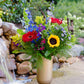 Colorful flower arrangement in a glass vase by a water feature