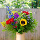 Colorful bouquet of flowers in a vase on a wooden table outdoors.